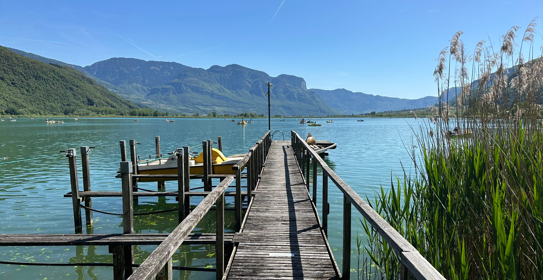 Holzsteg am Kalterer See mit Bergpanorama