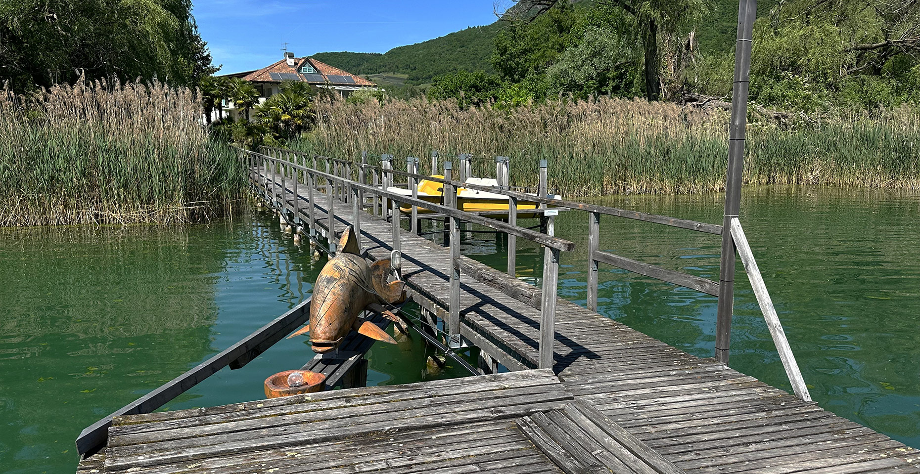 Holzsteg am Kalterer See mit Fischskulptur